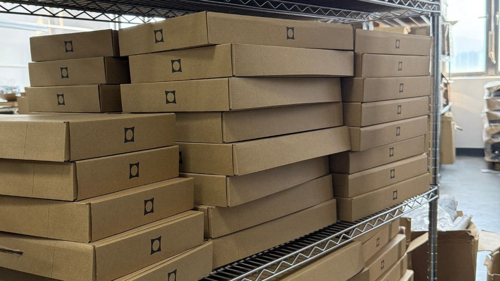 Shelves stacked with packed Monoblocc kit boxes at the factory, ready for Batch 6 shipping