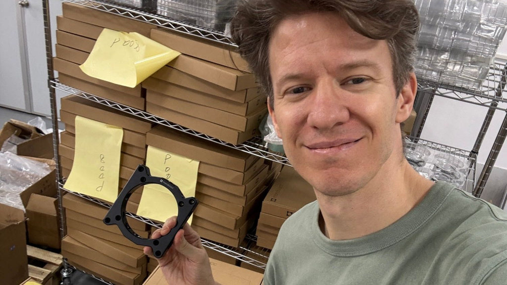 Wolfgang smiling and holding a CNC-machined Monoblocc VESA plate at the factory